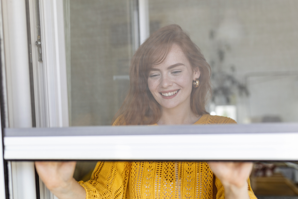 Woman hand hold retractable pleated insect screen holder to open or close the window ,mosquito nets
